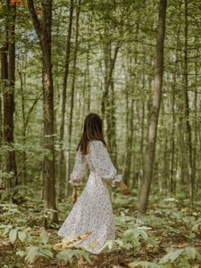 anonymous stylish woman strolling in green forest